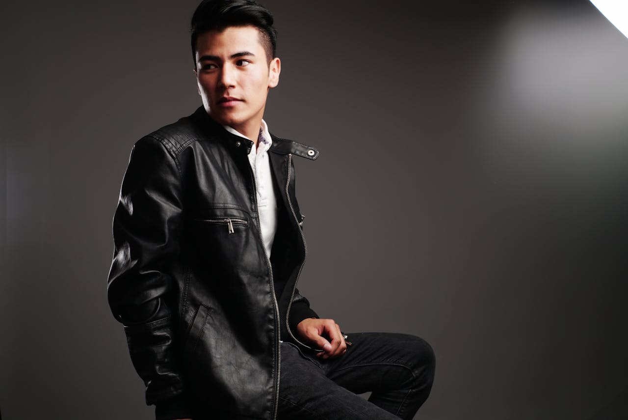 Elegant and modern portrait of a man wearing a black leather jacket in a studio setting.